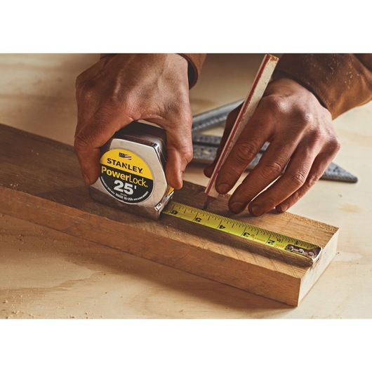 25 foot powerlock tape measure being used by a person to measure wood length.