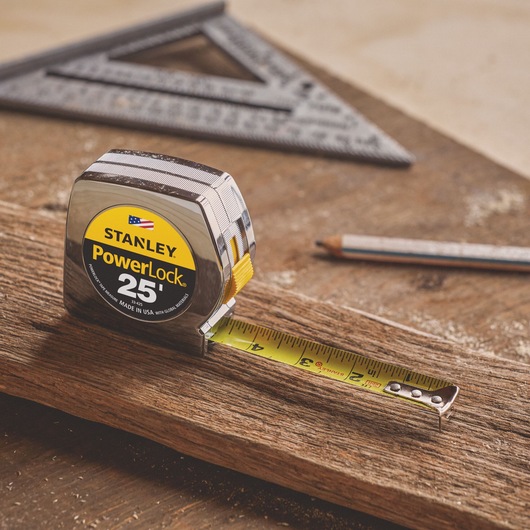 25 foot powerlock tape measure placed on a wooden plank with its ruler extended.