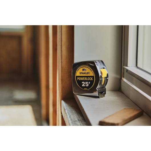 25 foot powerlock tape measure placed on a window sill indoors.